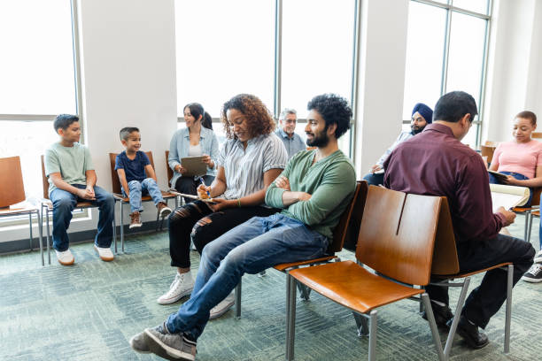 A large, multiracial group of people wait to see a medical professional.